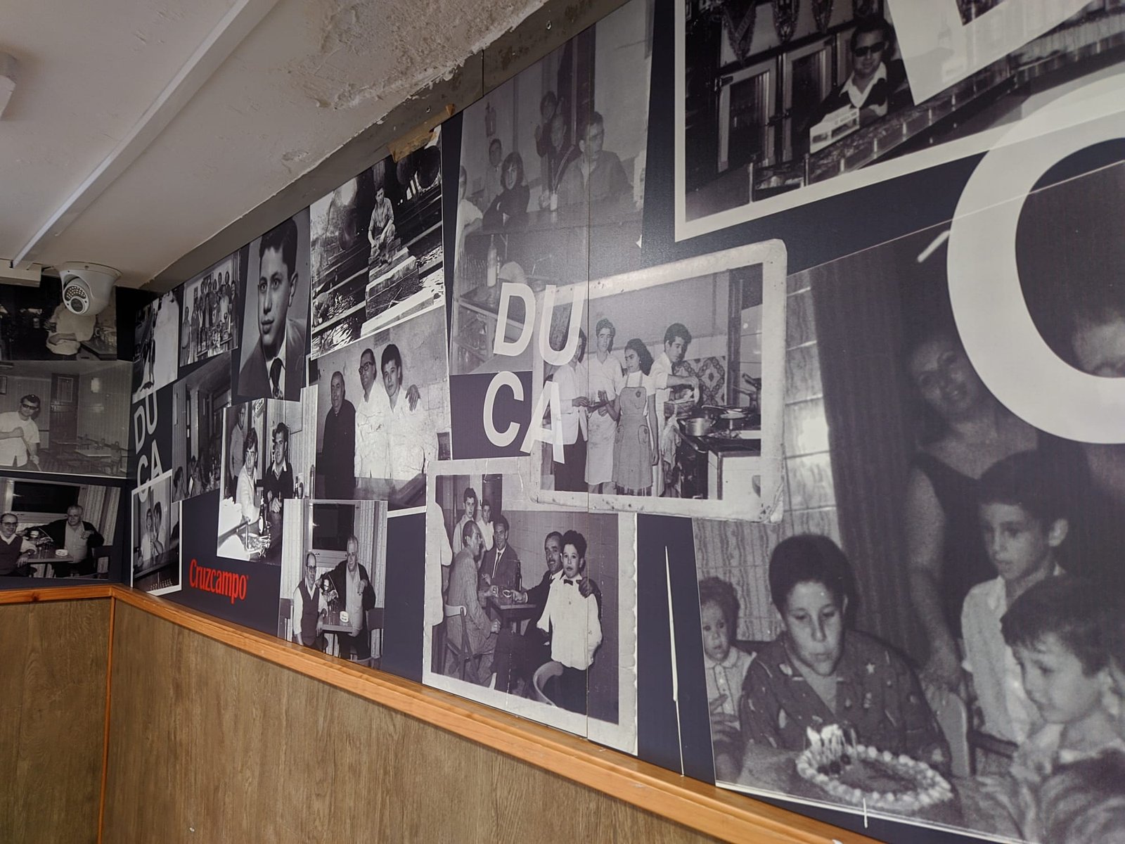Mural de fotografías históricas en el interior de Café Bar Ducal